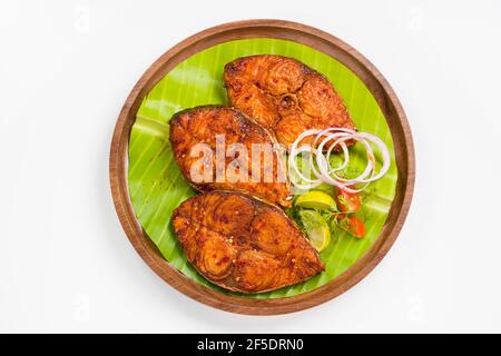 Seer Fish Braten schön angeordnet und garniert mit Zwiebel, Zitrone und Tomatenscheiben auf Holzplatte mit Bananenblatt ausgekleidet. Stockfoto