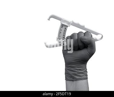 Ein Caliper zur Messung von subkutanem Fett, in der Hand in einem Gummihandschuh zu einer Faust zusammengedrückt, isoliert auf weißem Hintergrund, in grau. Stockfoto