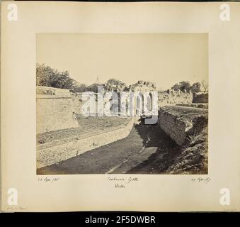 Delhi; Das Kashmir-Tor. Blick auf das Kashmiri-Tor entlang der Nordwand von Alt-Delhi. Ruinen der Steinmauer um die Stadt flankieren beide Seiten des Tores, das zwei Seite-an-Seite spitzen Bögen auf einer Seite einer hölzernen Brücke über einen trockenen Graben gebaut verfügt. Die Spitze eines Kuppelgebäudes ist über den Bäumen im Hintergrund zu sehen, und zwei Männer stehen auf der Brücke mit Blick auf die Kamera. (Recto, Bild) Unten links, im Negativ handschriftlich: '1357' (Recto, Montierung) Unten links, in schwarzer Tinte handschriftlich: '26 Sept /65' Unten links, in Bleistift handschriftlich: 'A42,10 (Bou)' Unten Mitte, in schwarz handschriftlich Stockfoto