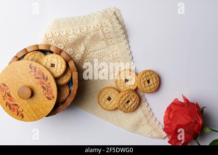 Eine Rose und runde Kekse in einer Tasse auf einem Serviette auf weißem Hintergrund Stockfoto