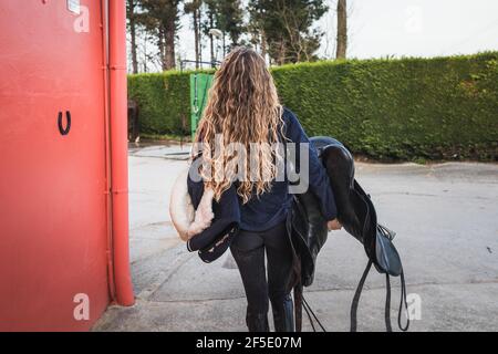 Junge kaukasische Frau mit einem Reitsattel in einem Reitsport Zentrieren Stockfoto