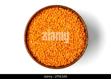 Rohe Samen von Orangenlinsen in Holzschüssel, Löffel isoliert auf weißem Hintergrund Draufsicht Flat Lay gesunde Ernährung, pflanzliches Protein-Konzept traditionell Stockfoto