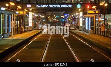 Berlin, Deutschland. März 2021, 24th. Blick über die Straßenbahnschienen bis zur beleuchteten Aufschrift 'Bahnhof Friedrichstraße'. Aufgrund der Einschränkungen durch die Corona-Pandemie gibt es am späten Abend kaum Menschen auf der ansonsten belebten Friedrichstraße. Quelle: Stefan Jaitner/dpa/Alamy Live News Stockfoto