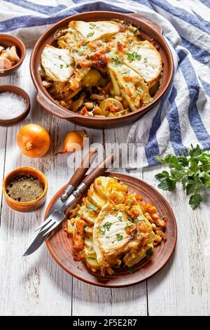 Tartiflette, French Potato, Bacon und Käse Auflauf in einer Tonplatte und eine Portion auf einem Teller, französische Küche Stockfoto