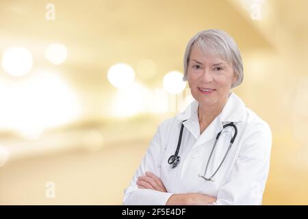 Porträt eines lächelnden medizinischen Regisseurs mit Stethoskop, verwischter gelber Hintergrund, Kopierraum. Stockfoto