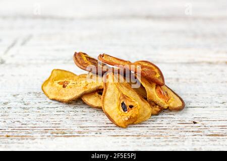 Ein Stapel getrockneter Birnen in Scheiben auf weißem Holzgrund. Getrocknete Fruchtchips. Gesundes veganes Essen. Stockfoto