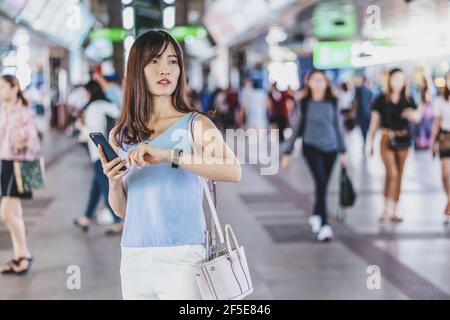 Junge asiatische Frau Passagier Überprüfung der Zeit und warten auf Ihr Freund in U-Bahn-Zug, wenn Reisen in der großen Stadt, japanisch, chinesisch, koreanisch Lifestyle Stockfoto