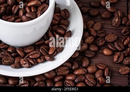 Kaffeetasse und eine Streuung von Kaffeebohnen auf einer Bambusserviette. Stockfoto