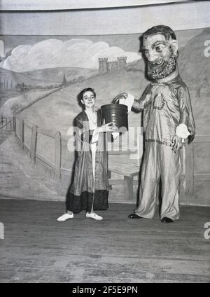 1956, historisch, stehend auf einer Bühne zwei Schauspieler in den Kostümen ihrer Charaktere - Jack und der Riese - aus dem Stück, Jack & the Beanstalk, England, Großbritannien. Eine uralte Volksgeschichte, die zuerst als englisches Märchen veröffentlicht wurde, „The Story of Jack Spriggins and the Enchanted Bean“ im Jahr 1734 und dann 1807 in „The History of Jack and the Bean-Stiel“ von Benjamin Tabert. Märchen sind alte Folklore, featuriing mythische Kreaturen; Elfen, Feen, sprechende Tiere, Hexen und Riesen in magischen Geschichten, die weit hergeholt und nicht wahr sind und in der Tat möglicherweise nicht wahr sein könnten. Stockfoto