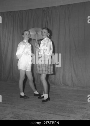 1954, historisch, auf einer Bühne vor dem Vorhang in ihren Kostümen, stehen zwei junge Schauspielerinnen für ein Foto, bevor sie in der Pantomime, 'Mother Goose', England, Großbritannien, auftreten. Ursprünglich der imaginäre Autor einer Sammlung von französischen Märchen und später von englischen Kinderreimen, wird gesagt, dass die Figur von Mother Goose zum ersten Mal im Jahr 1806 als die Performance erschien, "Harlekin und Mother Goose" oder "das goldene Ei". Verschiedene Pantomime-Adaptionen der Mutter-Gans-Geschichte wurden während der 19th und 20th Jahrhunderte fortgesetzt, aber es ist eine beliebte Familie Unterhaltungsshow geblieben. Stockfoto