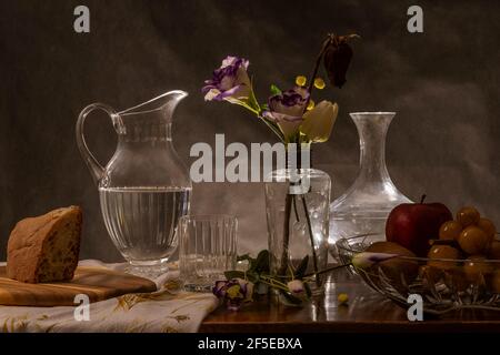 Ein Holztisch ist mit Speisen, Getränken und einer Glasvase mit Blumen eingerichtet Stockfoto