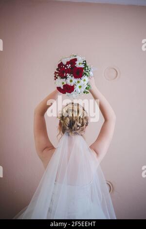 Vertikale Rückansicht einer Braut, die einen Strauß hält Ihr Kopf, bevor sie es werfen Stockfoto