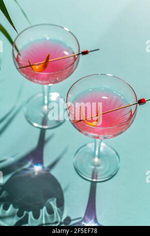 Ein Cocktail in einem Glas mit rotem Chilli und einem Schneidebrett mit Pfeffer, Ingwer-Zutaten im Hintergrund. Stockfoto