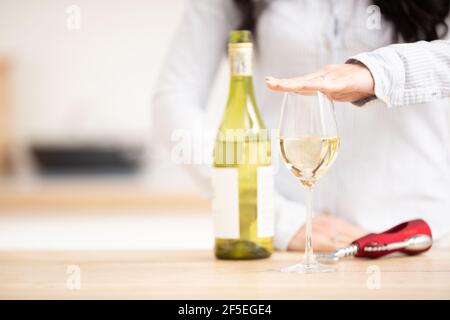 Frau, die Hand über das Glas Weißwein hielt, um auszudrücken, dass sie genug hatte. Stockfoto