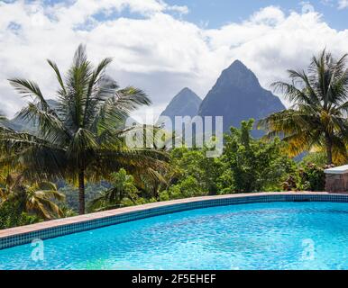 Soufriere, St. Lucia. Blick auf die Pitons über den leeren Swimmingpool, Kokospalmen am Hang. Stockfoto