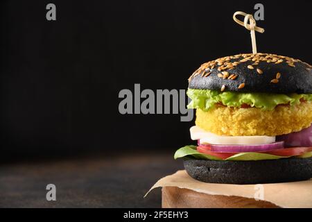 Trendy vegan Burger von schwarzen Brötchen, Gemüse Fleischbällchen Pflanzen Fleisch auf schwarzem Tisch. Nahaufnahme. Speicherplatz kopieren. Stockfoto