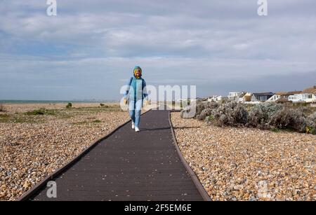 Shoreham-by-Sea Großbritannien 26th March 2021 - EIN Wanderer genießt die Mischung aus Sonnenschein und Duschen entlang Shoreham Beach Promenade in Sussex heute : Credit Simon Dack / Alamy Live News Stockfoto