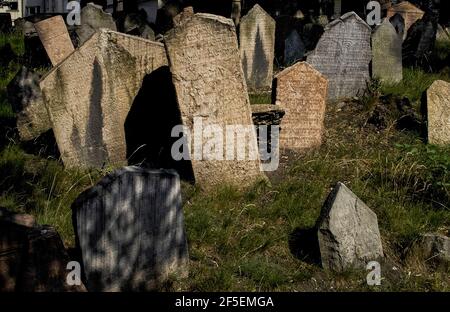 Die über 12.000 Grabsteine auf dem Alten Jüdischen Friedhof in Prag, der Hauptstadt Tschechiens, verbergen 100.000 frühere Bestattungen in bis zu 12 unterirdischen Schichten. Der Friedhof, der fast 350 Jahre lang genutzt wurde, erwies sich als zu klein und als Leichenlagen wurden alte Grabsteine auf die neue Oberfläche gehoben. Die frühesten tragen nur hebräische Inschriften, aber spätere Beispiele weisen Symbole auf Namen, Charakter oder Beruf hin. Neben Tieren wie Löwen, Bären und Wölfen gibt es Harfen oder Geigen für Musiker, Lanzetten für Ärzte und Scheren für Schneider. Stockfoto