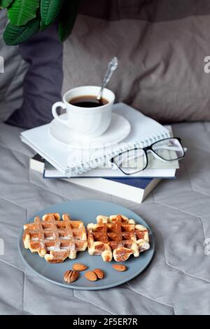 Frühstück im Bett - Belgische Waffeln mit Sauce und eine Tasse Kaffee auf einem Holztablett Stockfoto