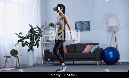 Glückliche junge Frau in Sportswear und vr Headset beim Trainen Zu Hause Stockfoto