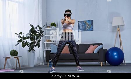 Junge Frau in Sportbekleidung und vr Headset-Gaming zu Hause Stockfoto