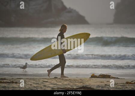 Surfer mit gelbem Surfbrett am Strand von Morro Bay in San Luis Obispo, Kalifornien. Stockfoto