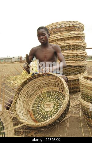 Ein Junge webt einen Korb in der Außenwand des Staates Ondo, Nigeria. Stockfoto