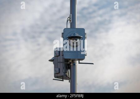 Zwei große Überwachungskameras auf einem Lichtmast am wolkigen Himmel mit Wolken im Hintergrund, gedimmtes Licht, tagsüber ohne Menschen, Stockfoto