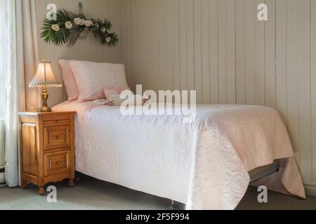 Einzelbett und Nachttisch aus Kiefernholz im Gästeschlafzimmer mit Grüner Teppich im oberen Stockwerk in einem alten Cottage aus dem Jahr 1807 Haus im Stil Stockfoto