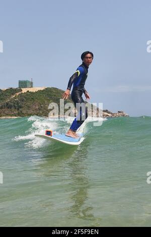 (210326) -- SANYA, 26. März 2021 (Xinhua) -- Foto vom 27. Februar 2021 zeigt Yang Xingfu beim Surfen im Dorf Tenghai in Sanya, südchinesische Provinz Hainan. Das Dorf Tenghai, einst ein kleines Fischerdorf, ist seit dem Surfboom in China ein berühmtes Surfcamp geworden, nachdem es offiziell für das Programm der Olympischen Spiele 2020 in Tokio zugelassen wurde. Das Dorf liegt in Sanya, der südchinesischen Provinz Hainan, und gewann auch Anerkennung für seine großartige Kombination aus Wassersport und Tourismusindustrie.Yang Xingfu, ein örtlicher Dorfbewohner, ist einer der frühesten Surfer in Tenghai. Yang verlobt sich einmal Stockfoto