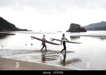 (210326) -- SANYA, 26. März 2021 (Xinhua) -- das Foto vom 27. Februar 2021 zeigt Surfenthusiasten, die sich im Dorf Tanya in Tenghai, der Provinz Hainan in Südchina, auf das Surfen vorbereiten. Das Dorf Tenghai, einst ein kleines Fischerdorf, ist seit dem Surfboom in China ein berühmtes Surfcamp geworden, nachdem es offiziell für das Programm der Olympischen Spiele 2020 in Tokio zugelassen wurde. Das Dorf liegt in Sanya, der südchinesischen Provinz Hainan, und gewann auch Anerkennung für seine großartige Kombination aus Wassersport und Tourismusindustrie.Yang Xingfu, ein örtlicher Dorfbewohner, ist einer der frühesten Surfer in Tenghai. Yang ein Stockfoto