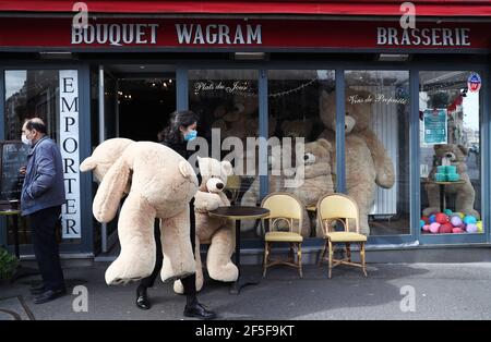 Paris, Frankreich. März 2021, 26th. Der Besitzer des Bouquet Wagram Cafés, das Take Away Dienstleistungen bietet, trägt einen riesigen Teddybären in Paris, Frankreich, 26. März 2021. Der französische Gesundheitsminister Olivier Veran kündigte am Donnerstag "Zwangsbremsungsmaßnahmen" in drei weiteren COVID-19-Hochrisikoregionen - Rhone, Aube und Nievre - an, um eine dritte Welle der Pandemie einzudämmen. Kredit: Gao Jing/Xinhua/Alamy Live Nachrichten Stockfoto