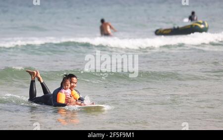 (210326) -- SANYA, 26. März 2021 (Xinhua) -- das Foto vom 27. Februar 2021 zeigt, wie TU Hongwei (R) seine Tochter beim Surfen im Dorf Tenghai in Sanya, der südchinesischen Provinz Hainan, nimmt. Das Dorf Tenghai, einst ein kleines Fischerdorf, ist seit dem Surfboom in China ein berühmtes Surfcamp geworden, nachdem es offiziell für das Programm der Olympischen Spiele 2020 in Tokio zugelassen wurde. Das Dorf liegt in Sanya, der südchinesischen Provinz Hainan, und gewann auch Anerkennung für seine großartige Kombination aus Wassersport und Tourismusindustrie.Yang Xingfu, ein örtlicher Dorfbewohner, ist einer der frühesten Surfer in Tenghai. Yang o Stockfoto