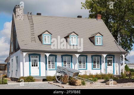Alt um 1790 weiß bemaltes vertikales Kiefernholz mit Blau Trimmen Sie die Fassade des Hauses im kanadischen Cottage-Stil mit grauem Blech Dach im Sommer Stockfoto
