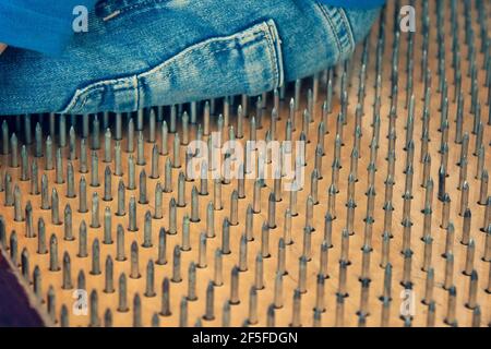 Die Person sitzt auf scharfen Nägeln. Person der entspannenden Bewegung, Stress, extrem Stockfoto