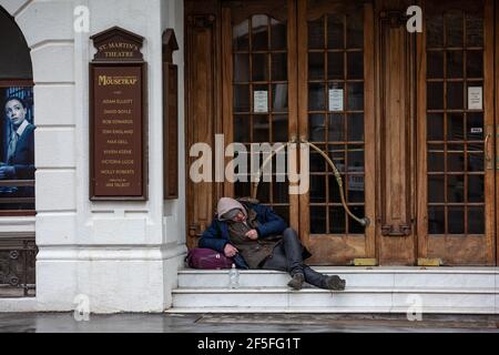 Ein Obdachloser sitzt auf den Stufen des St Martin's Theatre im Londoner West End, bevor die Coronavirus-Sperre die Produktion der Mousetrap inszenierte. Stockfoto