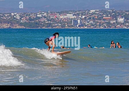 Junge Surferinnen reiten auf Surfbrettern an der Playa Zicatela in der Nähe von Puerto Escondido, San Pedro Mixtepec, Oaxaca, Mexiko Stockfoto