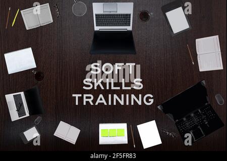 Draufsicht des Soft Skills Trainingstextes auf dem Tisch mit Laptops, Notizblock, Kaffee, Brillen, Stiften. Geschäftskonzept. Stockfoto