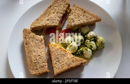 Ei- und Tomatenbrot auf braunem Brot und Mozzarella-Kugel In Öl und Kräutern Stockfoto
