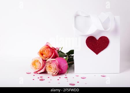 Rosen und Geschenk in Papierpackung mit rotem Herz Auf weißem Hintergrund/ Valentinstag Hintergrund Stockfoto