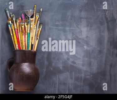 Pinsel in Tonkrug oder Topf auf abstrakten Tisch Hintergrund Textur malen. Kunstmaler Konzept Stockfoto