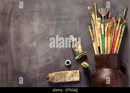 Pinsel und Tuben auf abstrakter Tischhintergrundstruktur malen. Art Painter Werkzeuge Konzept Stockfoto