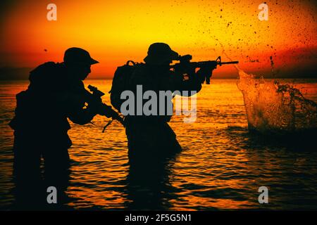 Armee Soldaten Team, spezielle Einsatzkräfte Infanteristen Landung auf See, zielen und schießen mit Service-Gewehr während des Brands an Land am Abend oder am Morgen Zeit. Militärische amphibische Operation Stockfoto