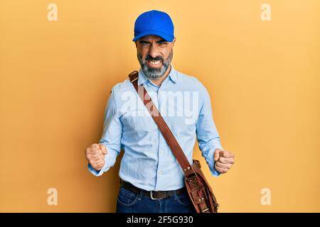 Mann mittleren Alters mit Bart und grauen Haaren trägt Lieferung Kuriermütze sehr glücklich und aufgeregt tun Sieger Geste mit den Armen angehoben, lächelnd und schreien Stockfoto