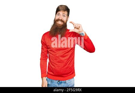 Rotschopf Mann mit langen Bart tragen lässige Kleidung lächelnd und Selbstbewusstes Gestik mit der Hand dabei kleine Größe Zeichen mit den Fingern Suchen und die Kamera Stockfoto