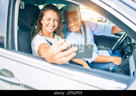 Mittelalterpaar verliebt sitzt im Auto gehen Für eine Reise, die ein Selfie-Bild mit Smartphone lächelt Glücklich und fröhlich zusammen Stockfoto