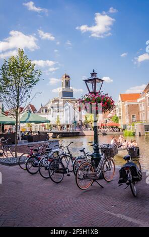 LEIDEN, NIEDERLANDE - 27. JUNI 2018: Radschar am Kanal und alte Laterne mit Blumen in Leiden, Niederlande Stockfoto