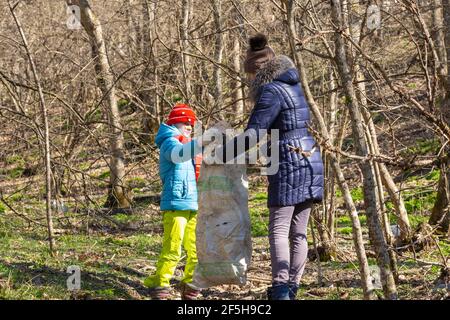 Ein Mädchen sammelt Müll im Wald, ein Mädchen hält einen großen Müllbeutel Stockfoto