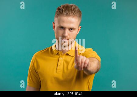 Porträt eines ernsten Mannes, der eine ablehnende Geste mit einem Stoppfinger zeigt. Kerl isoliert auf blauem Hintergrund. Stockfoto