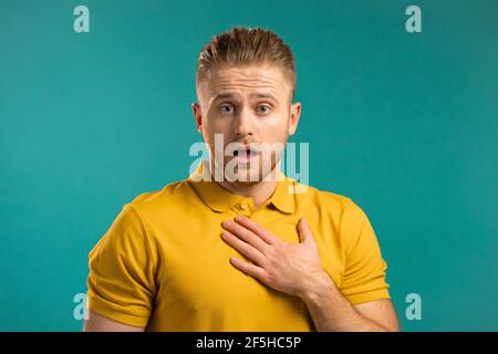 Europäischen Mann Angst vor etwas Angst und sieht in die Kamera mit großen Augen voller Entsetzen über blaue Wand Hintergrund. Stockfoto